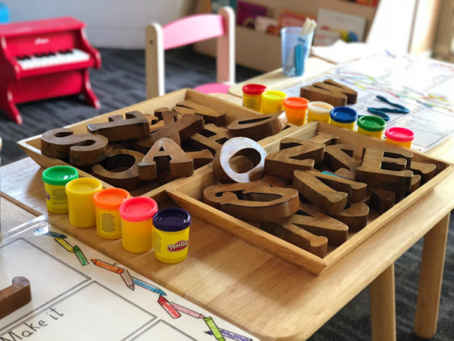 Comportamentos desafiadores podem muitas vezes demonstrar que a criança necessita de pausar em uma atividade. ( Na foto, uma mesa de atividades com letras em madeira). 