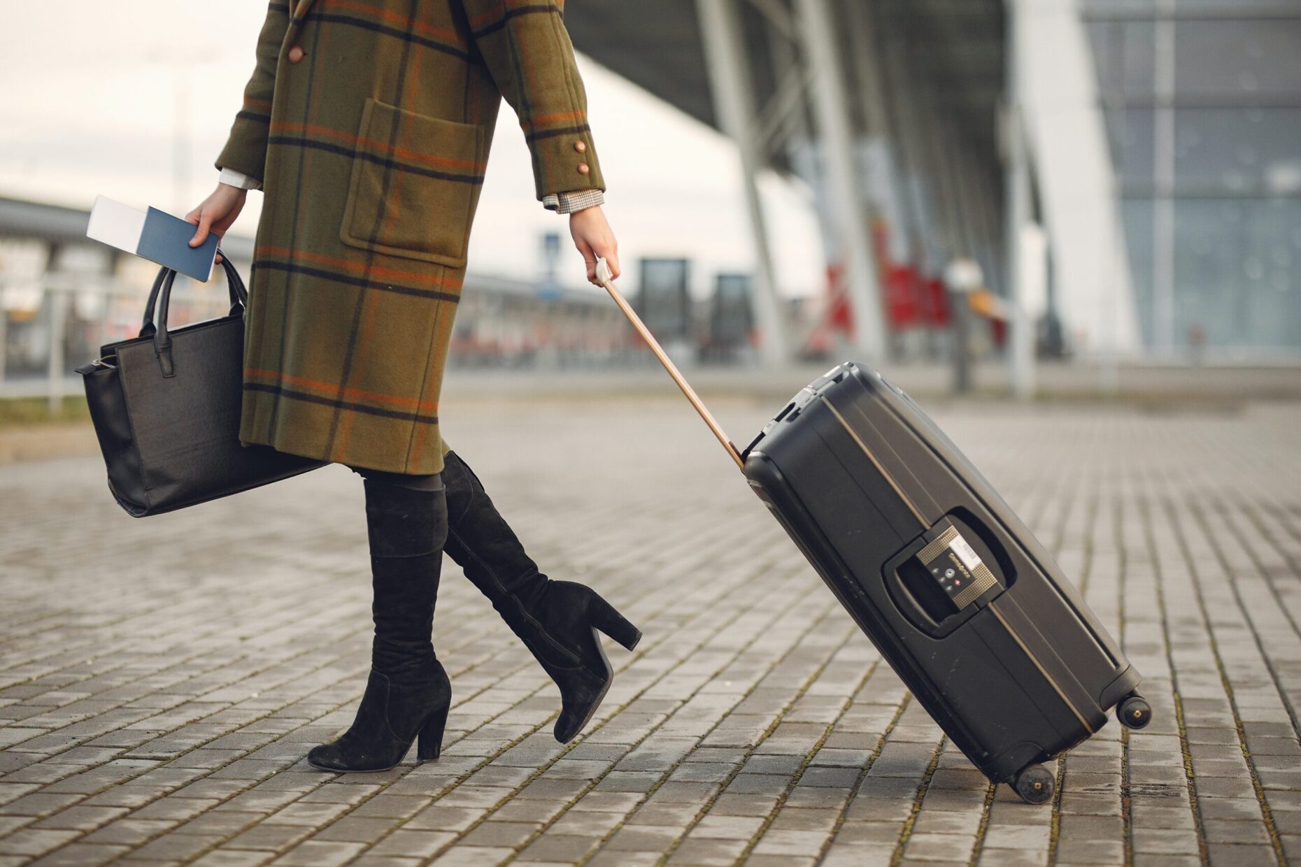 Nova medida pode reduzir gastos de brasileiros em viagens ao exterior. Na foto mulher carrega mala de viagem de rodinhas em uma mão e na outra uma bolsa de mão. Ela veste roupas de inverno. 