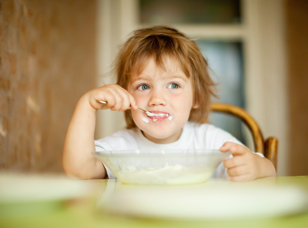 Seletividade alimentar no Autismo. Na foto, menino com uma colherada de alimento pastoso na boca. Imagem/Reprodução: bearfotos - Freepik