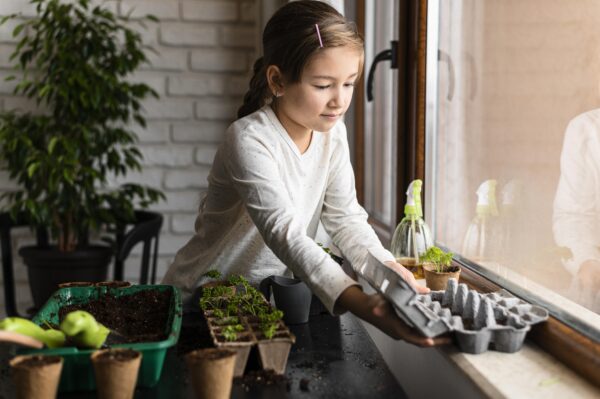 Na imagem, menina cuida de mudas em uma pequena horta em espaço interno. Essa prática pode ajudar autistas com seletividade alimentar a terem maior interesse por novos ingredientes. Imagem/Reprodução: Freepik 