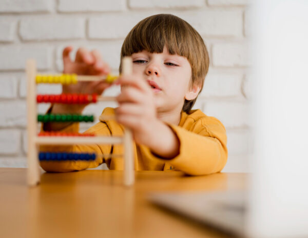 Na foto, menino em ambiente psicopedagógico manuseando um brinquedo que auxilia no aprendizado das cores e divisão soma. Imagem: Freepik