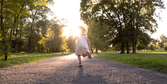 O eloping acontece quando uma pessoa autista foge de um local seguro e conhecido por ele e, nesse processo, acaba se perdendo de seus familiares e cuidadores. Na foto, garotinha correndo em um ambiente ao ar livre com muitas árvores ao redor. Foto/Reprodução: Freepik